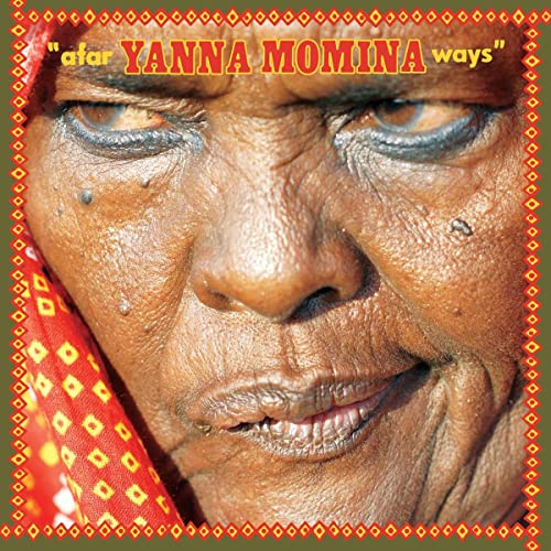 Close-up portrait of an elderly woman with patterned red head covering.