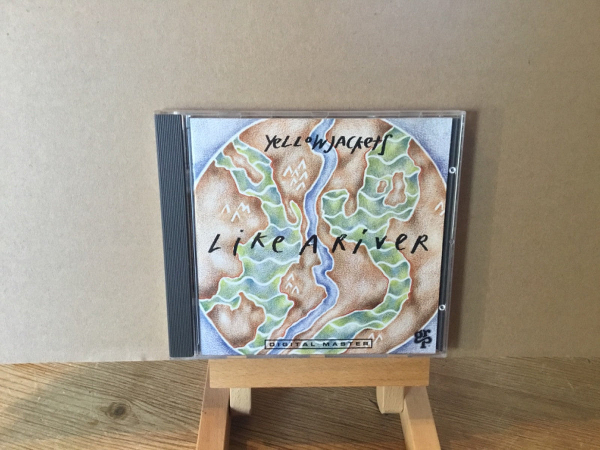 Yellowjackets "Like A River" CD in jewel case on a wooden stand.