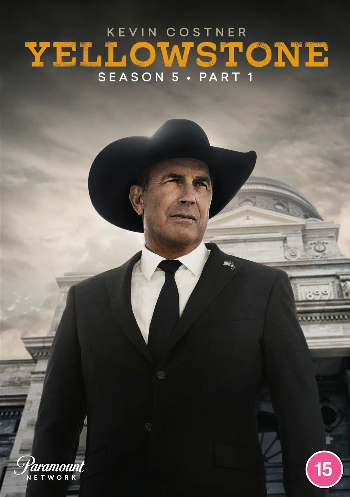Kevin Costner wears a cowboy hat and suit in front of a building, Yellowstone cover.