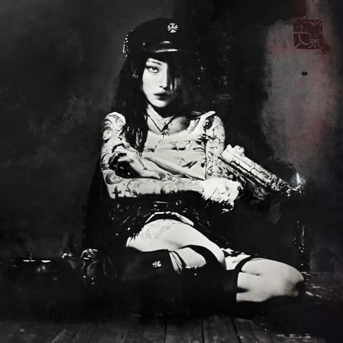 Black and white portrait of a tattooed woman in a cap holding a gun.