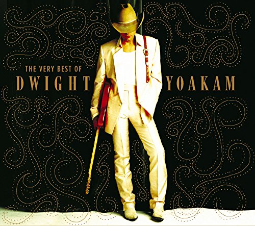 Dwight Yoakam in a light suit and cowboy hat holding a guitar against black.