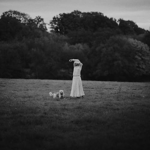 Black and white photo of a woman and dog in a field.