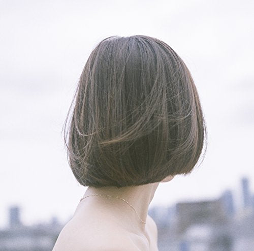 A person with a short brown bob haircut seen from behind against a blurred background.