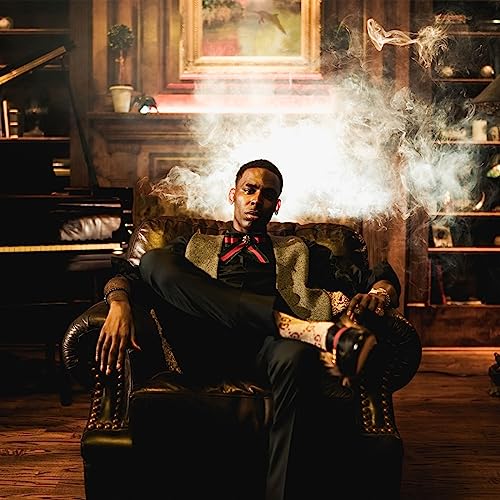 Young Dolph sits in a leather chair, surrounded by smoke and bookshelves.