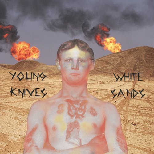 A shirtless man with tattoos stands before a desert landscape with explosions in the sky.