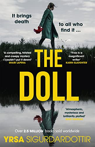 A person in a green coat walks near water, reflected below the title The Doll.