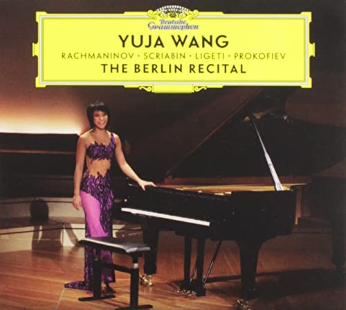Yuja Wang in purple dress stands beside a black grand piano.