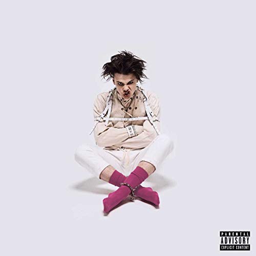 YUNGBLUD in a white straightjacket and pink socks sitting against a plain white background.