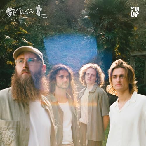 Four men with long hair stand in front of lush greenery.