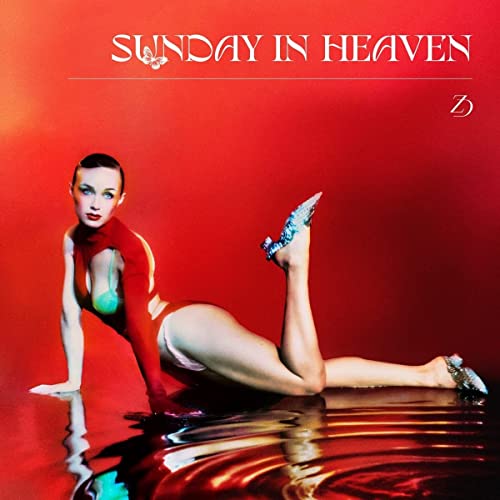Woman in red bodysuit and heels poses on water against a red background.