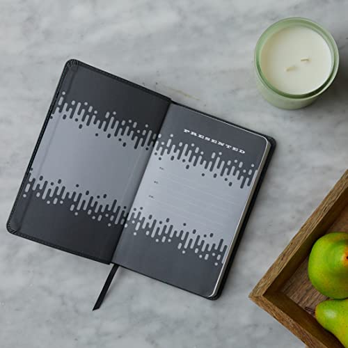 Open pink Bible with patterned edges, beside a candle and fruit.