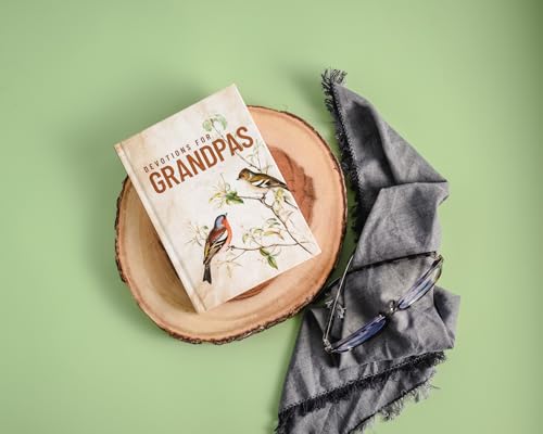 Book titled "Devotions for Grandpas" rests on wood with glasses and cloth.