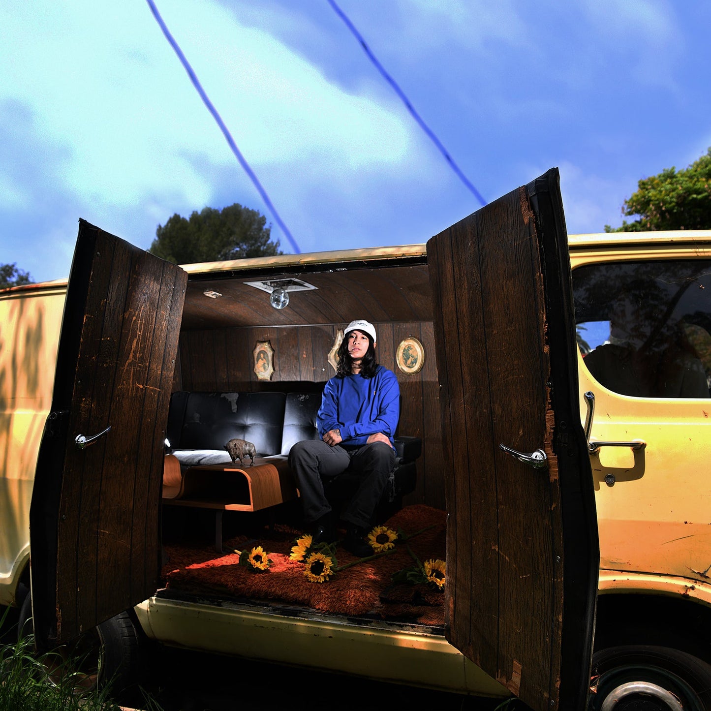 Person with long hair sits in a decorated, open van.