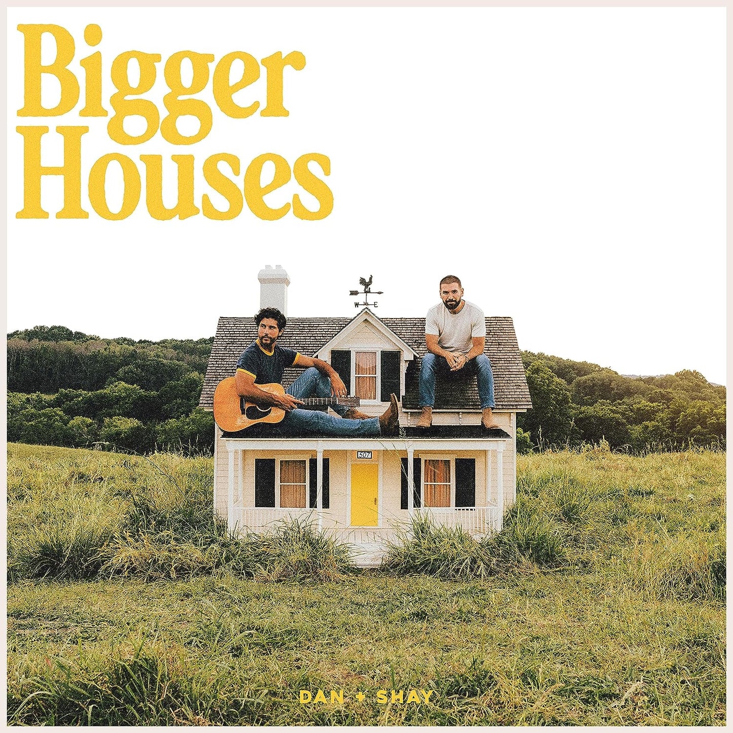 "Album cover with two men sitting on a small house in a field."