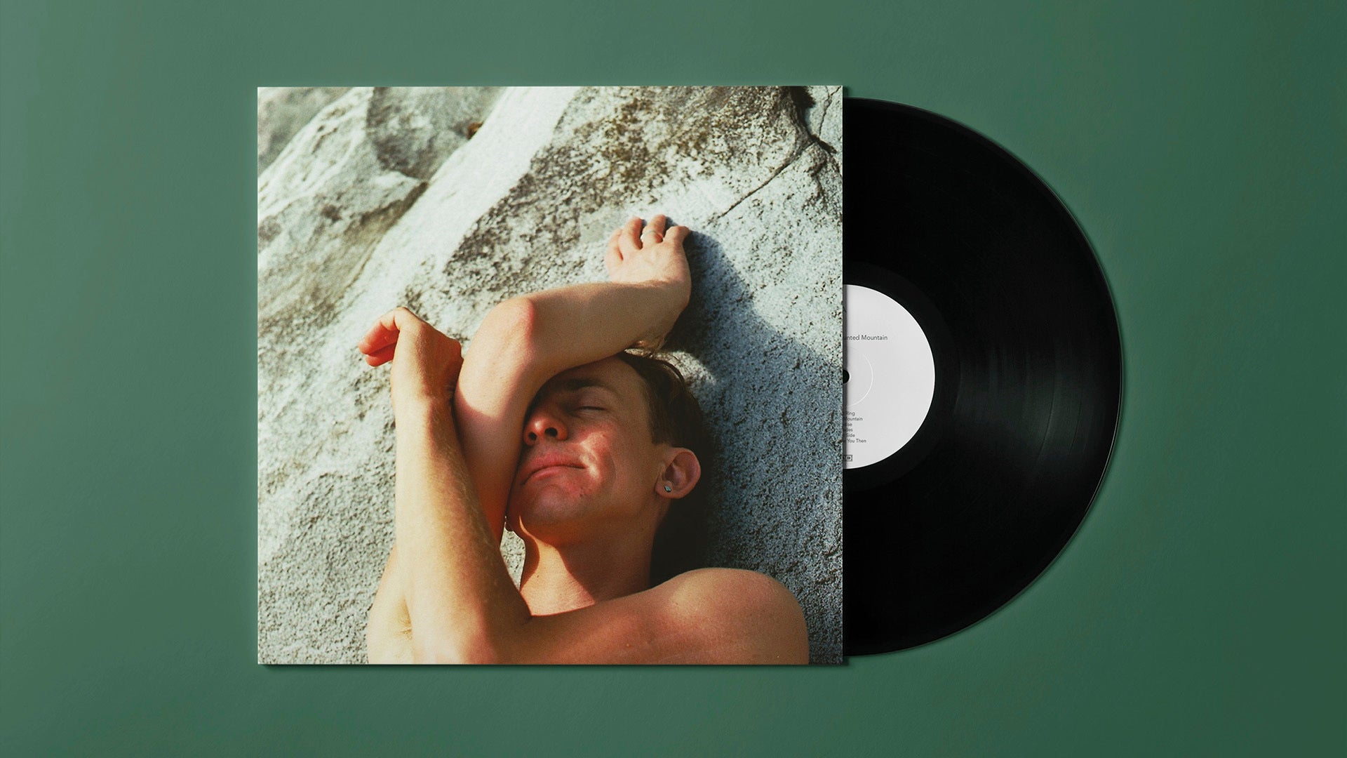 "Vinyl record sleeve with a man lying on rocks, partially showing a black vinyl."