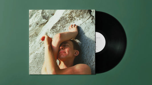"Vinyl record sleeve with a man lying on rocks, partially showing a black vinyl."