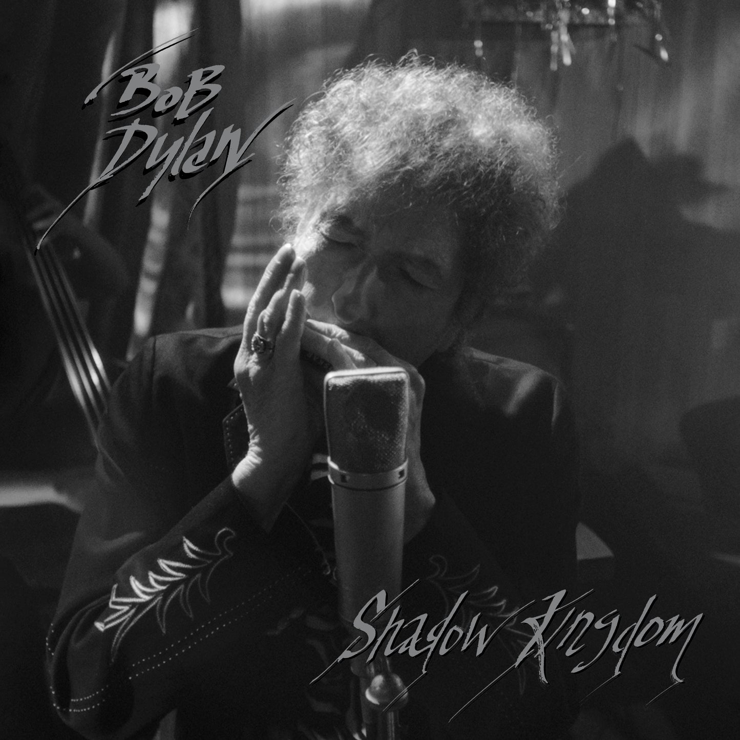 Black and white image of Bob Dylan singing into a microphone.