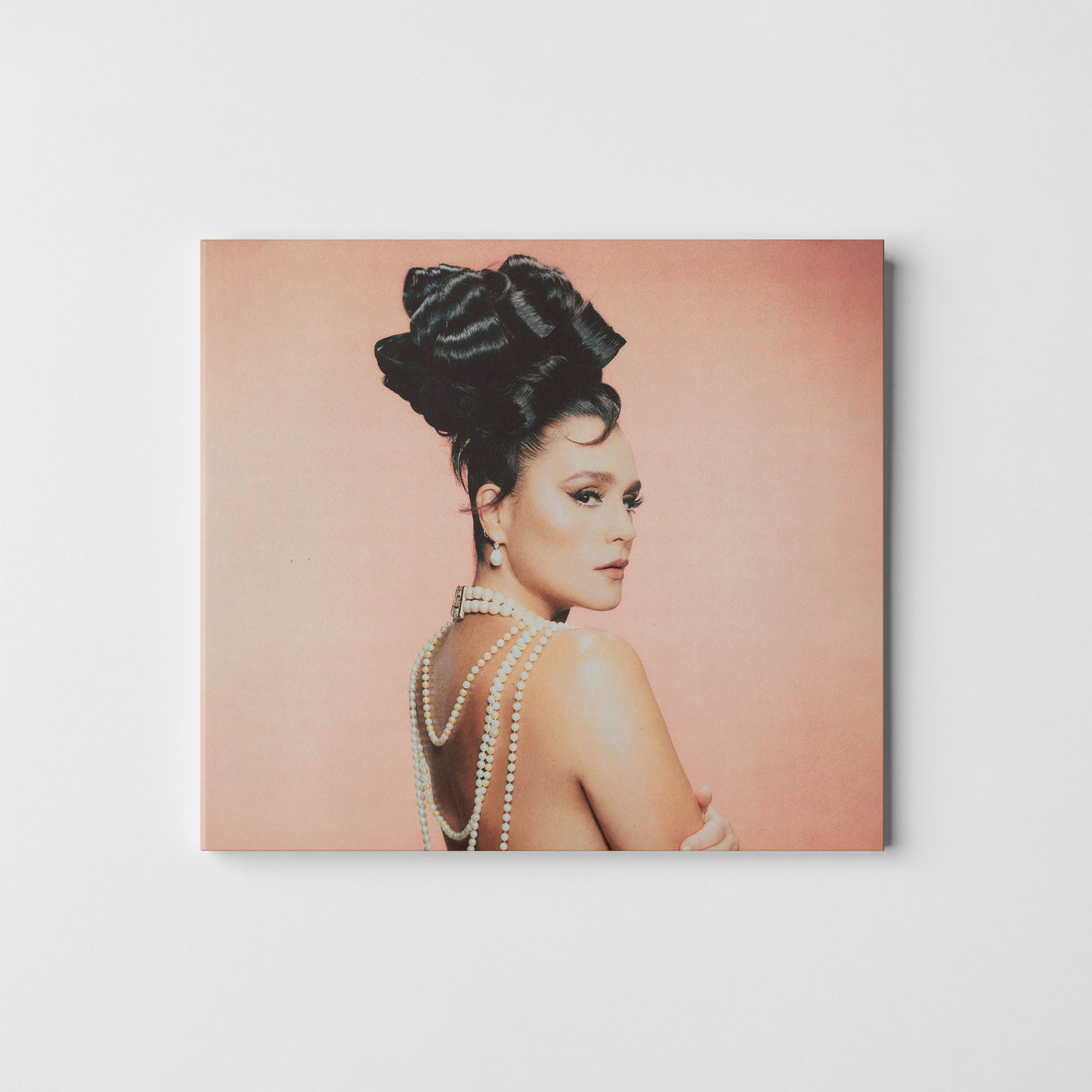 "CD cover featuring a woman with dark hair and pearl necklaces against a pink background."
