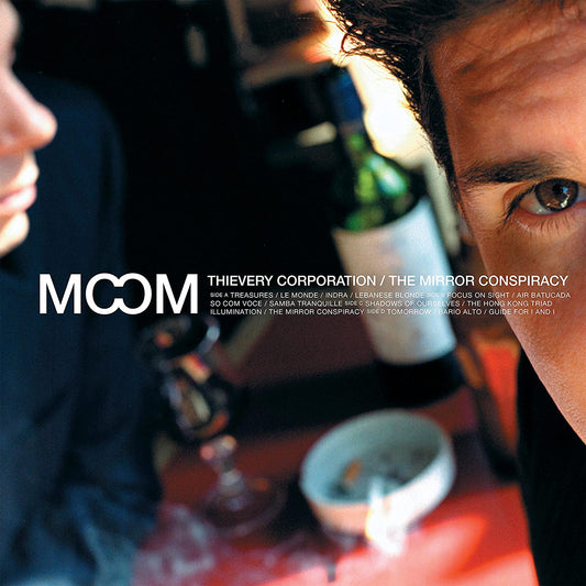 "Album cover with a man's face and a bottle on a red table."