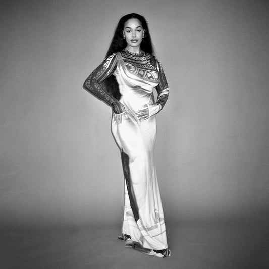 Black and white image of a woman in a long, patterned dress.