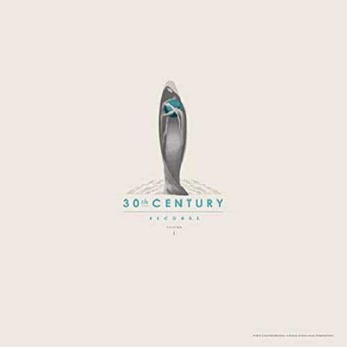 A vinyl record cover with a silver and blue abstract design on a beige background.