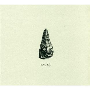 A sepia-toned image of a stone arrowhead with text "s.w.z.k" below it.
