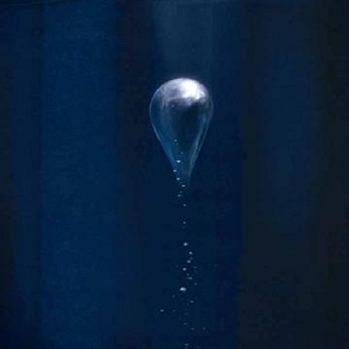 The image depicts a clear, teardrop-shaped object with a trail of smaller droplets beneath it. Alt text: "Clear teardrop-shaped object with droplets on a dark blue background."