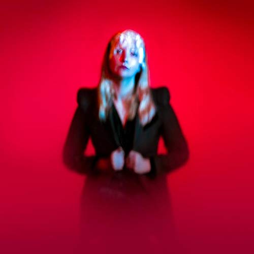 The alt text for the image is: "Blurry image of a woman with long blonde hair against a red background."