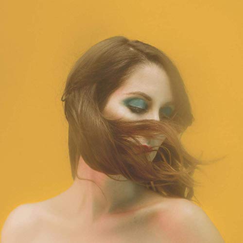 The alt text for the image is: "Woman with long brown hair covering her face against a yellow background."