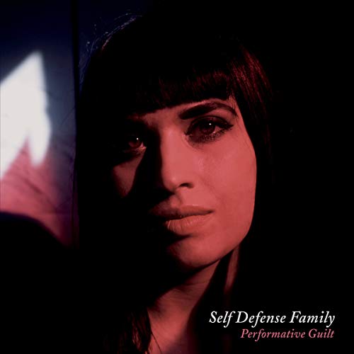 Album cover with a woman's face, dark and red-toned, with text "Self Defense Family Performative Guilt".