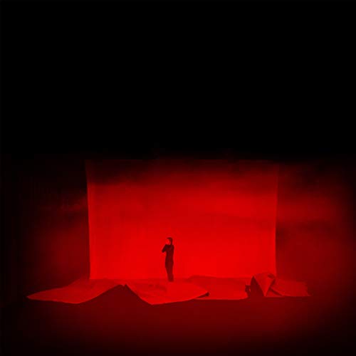 A vinyl record sleeve with a red-lit figure standing on crumpled paper.