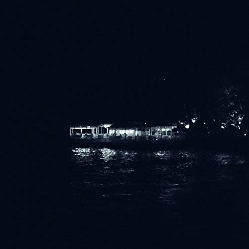 The image shows a dark body of water with a lit-up building in the distance. The alt text for this image could be: "Dark water with a lit building in the background."