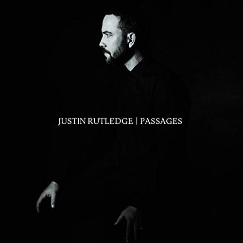 "Black and white image of a man, Justin Rutledge, on a dark background."