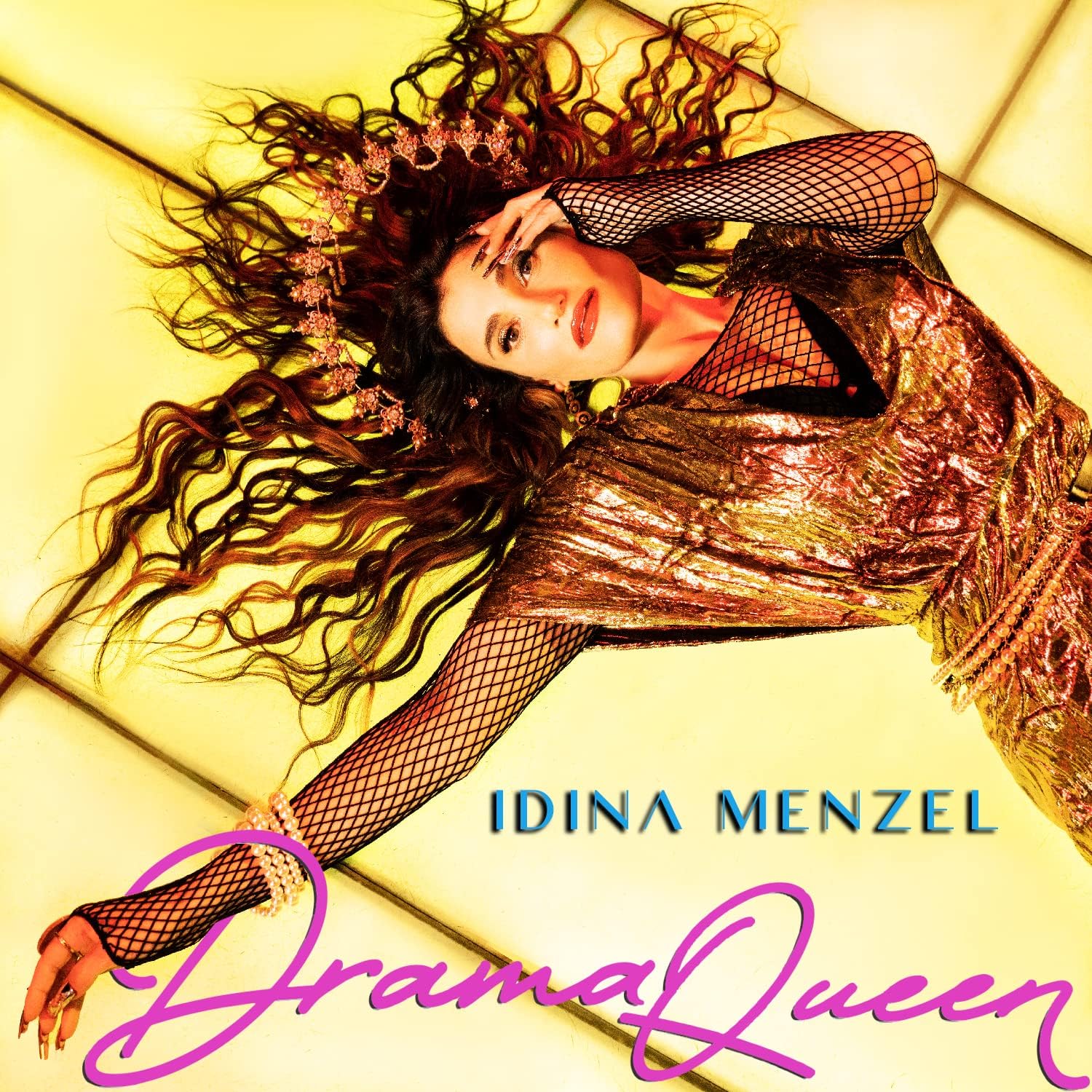 Idina Menzel lying on a yellow couch, wearing a shiny dress and fishnet sleeves.