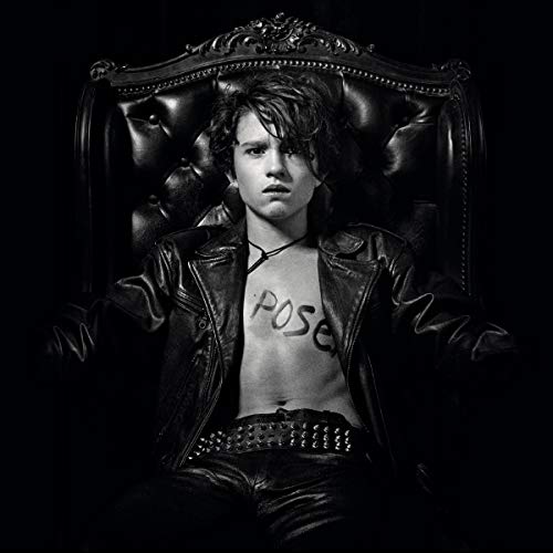 Black and white image of man sitting in ornate chair, shirtless with "POISON" written on chest.