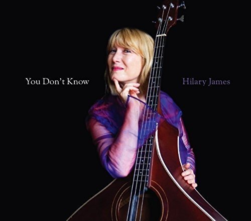 Album cover with blonde woman holding acoustic guitar against a black background.