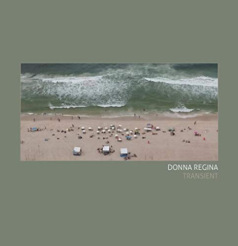 Aerial view of a crowded beach with waves and umbrellas on a greenish-gray background.
