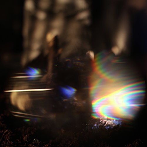 The image shows a CD with rainbow light reflections on a dark surface.