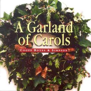 A Christmas wreath with green leaves and red ribbons, surrounding yellow text on a CD cover.