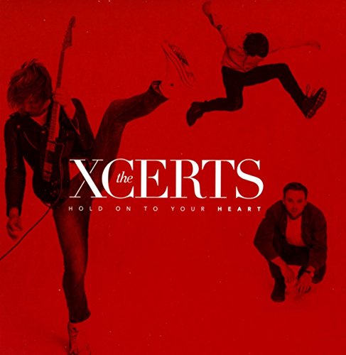 "Red album cover with three band members in dynamic poses, 'Xcerts' and 'Hold On To Your Heart' text."