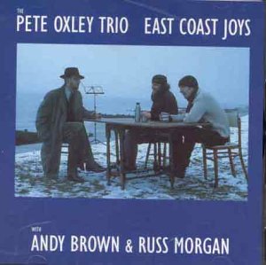 "Pete Oxley Trio CD cover featuring three men seated at a table outdoors."