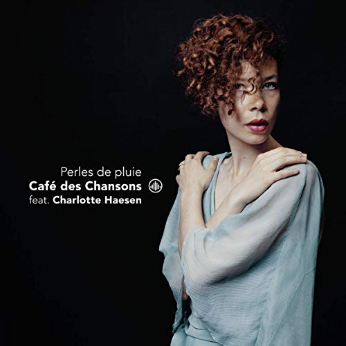A woman with curly red hair and light blue shirt is on a black album cover.