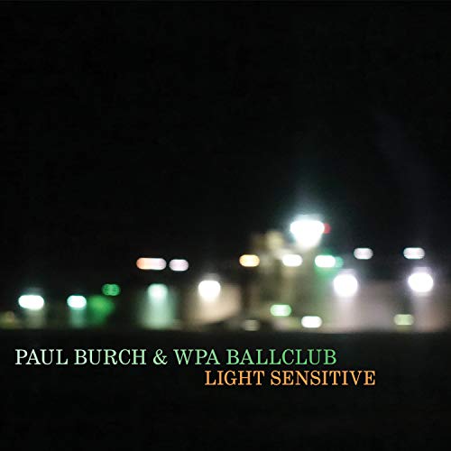 Album cover with blurry nighttime cityscape and multicolored text on a black background.