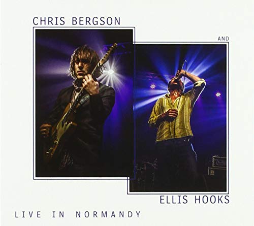 "Album cover featuring two men performing on stage under spotlights."
