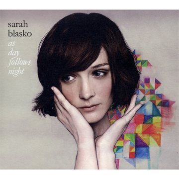 "Album cover featuring a woman with dark hair and a multicolored geometric pattern."