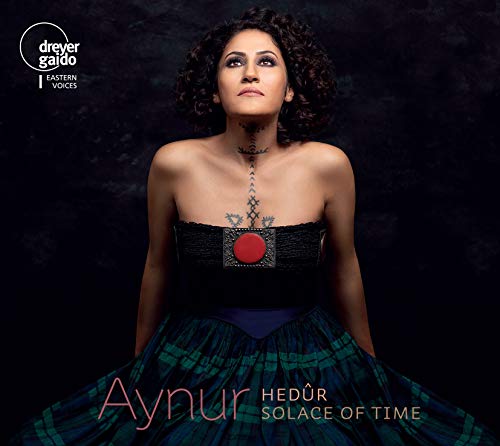 Aynur album cover: woman in black top and plaid skirt against dark background.