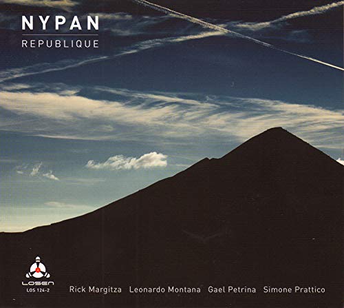 The image is a darkened mountain peak against a blue sky with wispy clouds.
