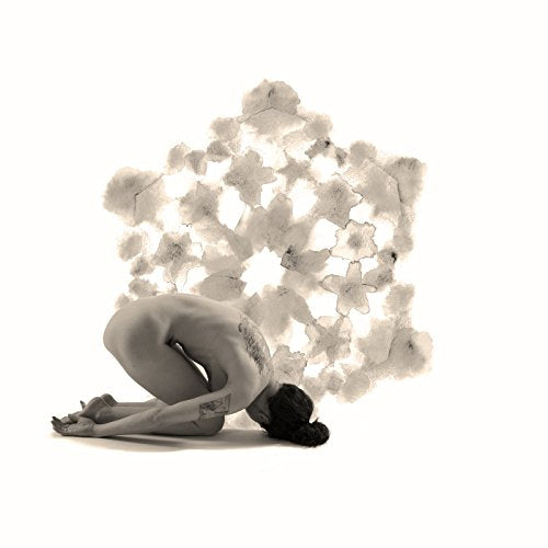 A woman crouches with her head down, surrounded by a cloud of white smoke.