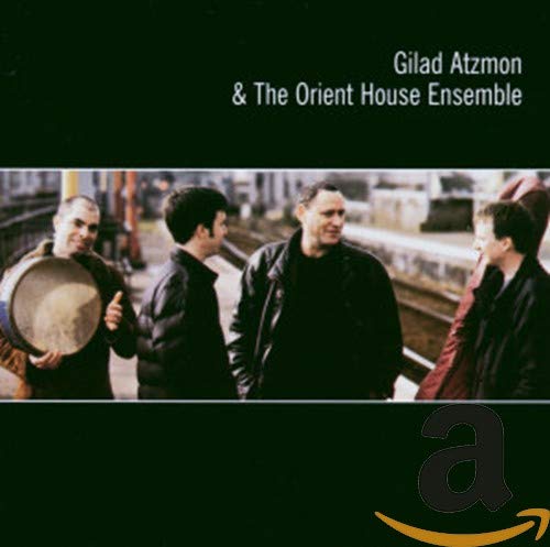 "CD cover with four men in dark clothing, one holding a drum, on a dark background."