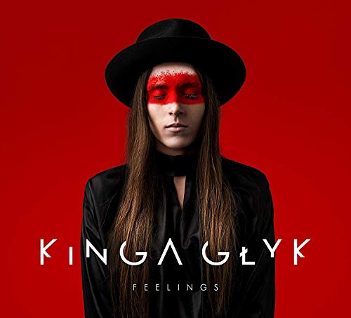 The image depicts a woman with red face paint, wearing a black hat and shirt, against a red background.